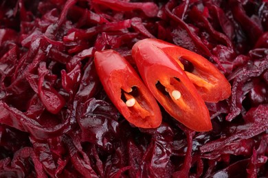 Tasty red cabbage sauerkraut with chili pepper as background, closeup