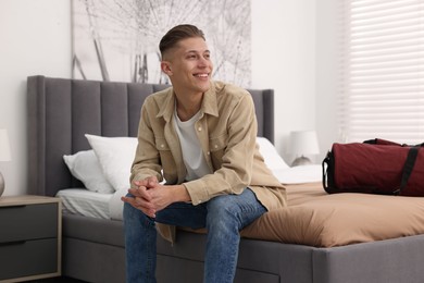 Smiling guest relaxing on bed in stylish hotel room