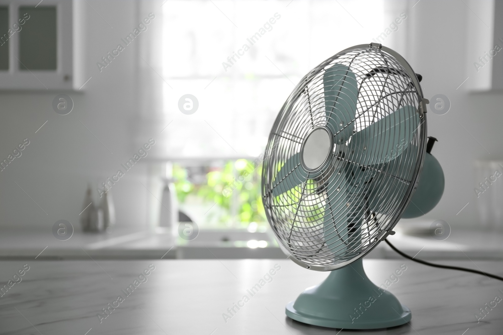 Photo of Modern electric fan on white marble table indoors, space for text. Summer heat