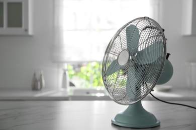 Photo of Modern electric fan on white marble table indoors, space for text. Summer heat