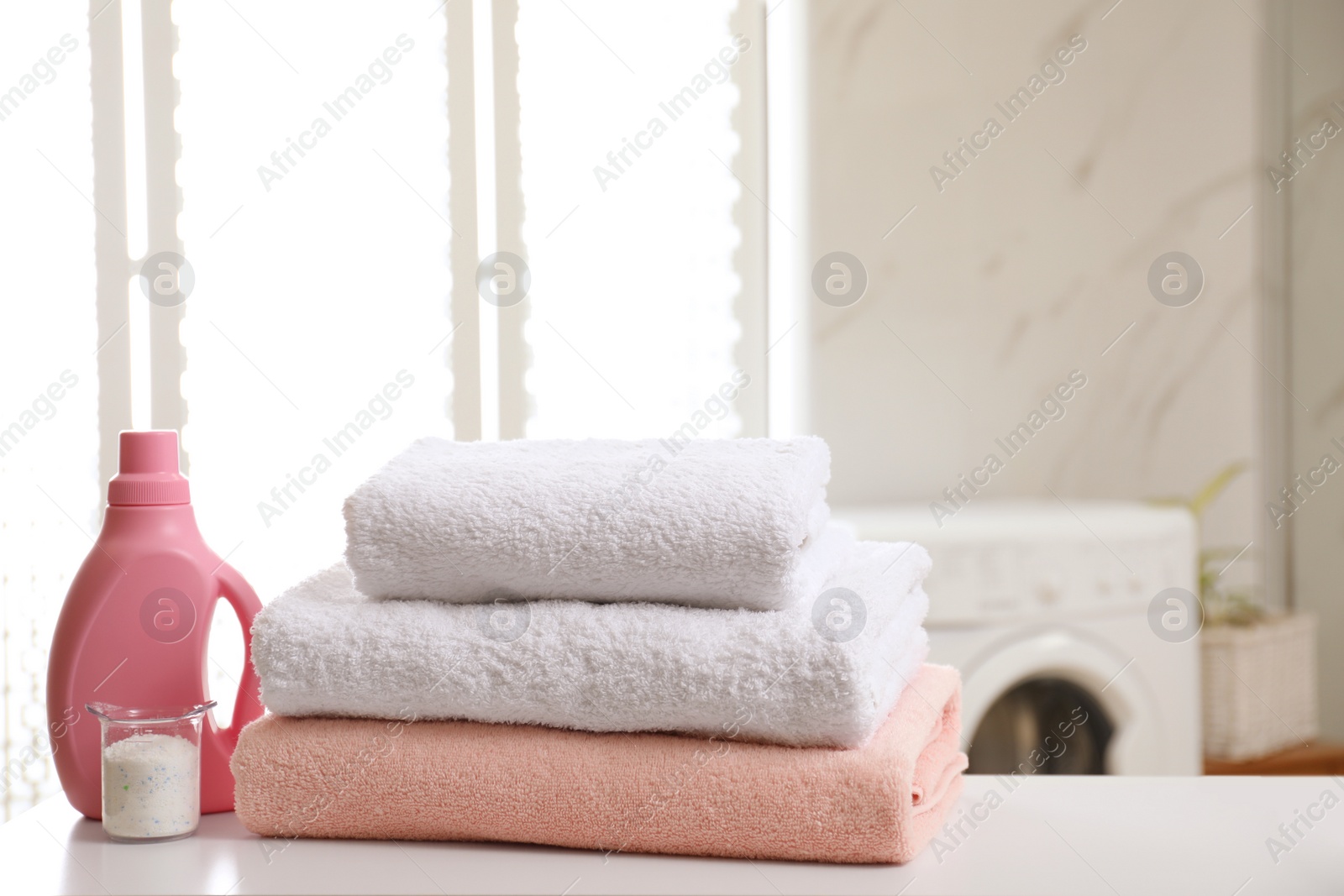 Photo of Clean towels and detergents on table in laundry room