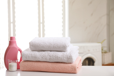 Photo of Clean towels and detergents on table in laundry room