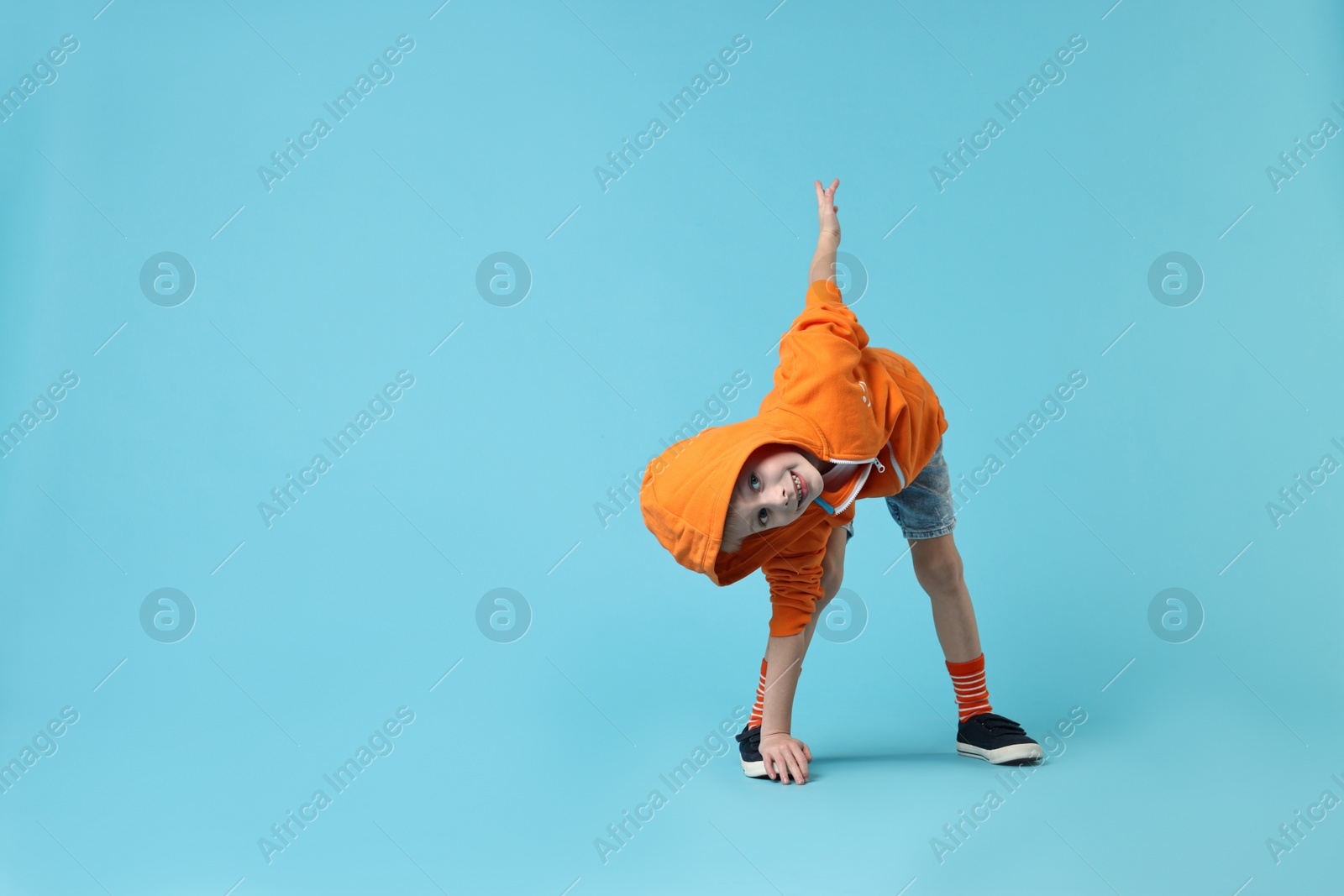 Photo of Happy little boy dancing on light blue background