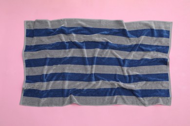Photo of Crumpled striped beach towel on pink background, top view