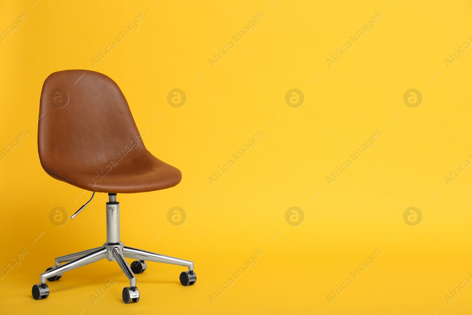 Photo of Modern office chair on yellow background. Space for text