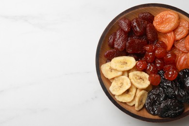 Mix of delicious dried fruits on white marble table, top view