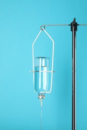 Photo of IV infusion set on pole against light blue background