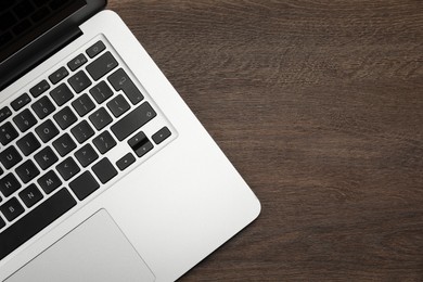 Photo of Modern laptop on wooden table, top view. Space for text