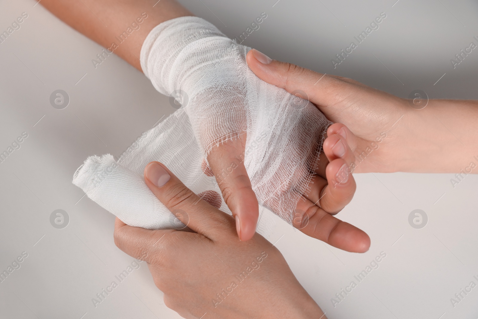 Photo of Doctor applying bandage onto patient's hand on white background, top view. Closeup