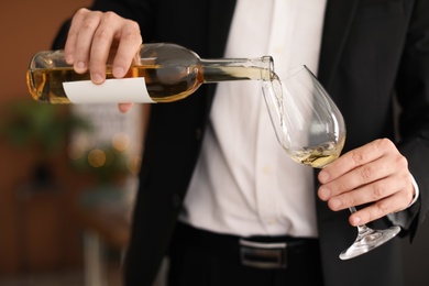 Photo of Man pouring delicious wine into glass indoors