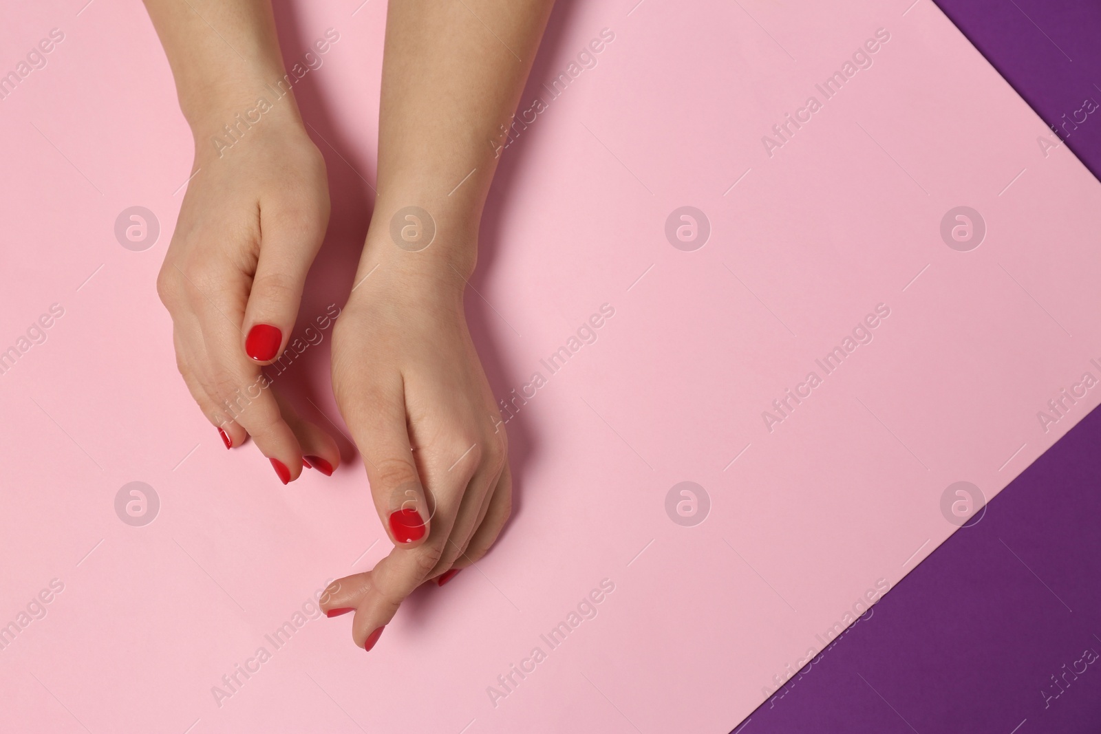 Photo of Woman showing red manicure on color background, top view with space for text. Nail polish trends