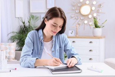 Photo of Young woman drawing in sketchbook at home