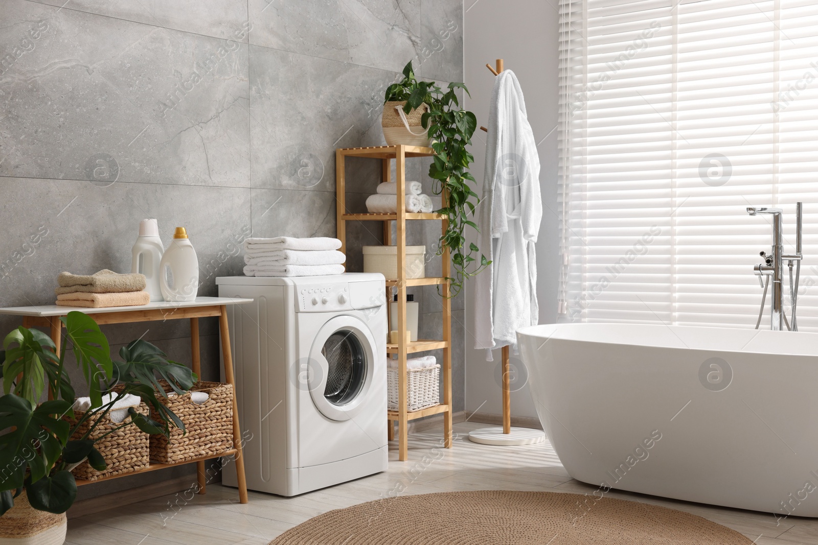 Photo of Clean towels, washing machine, plants and deterrents in bathroom