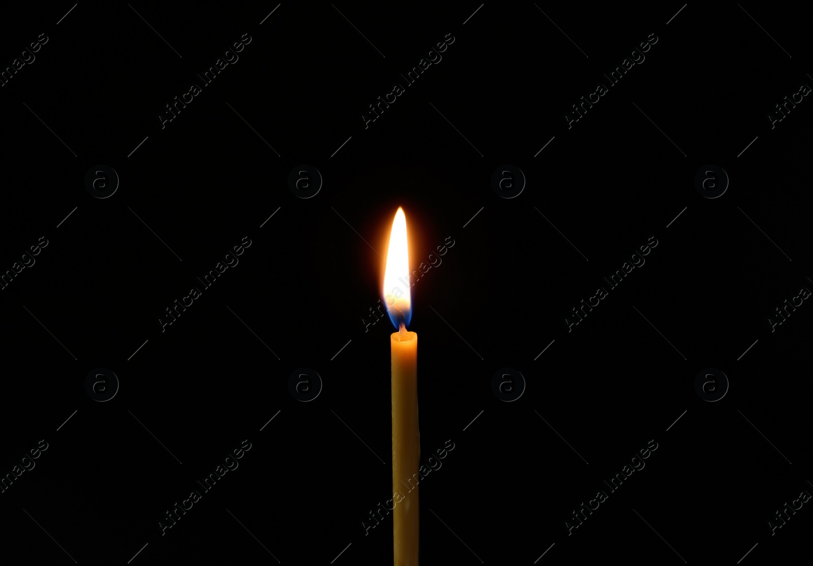 Photo of One burning church candle on dark background