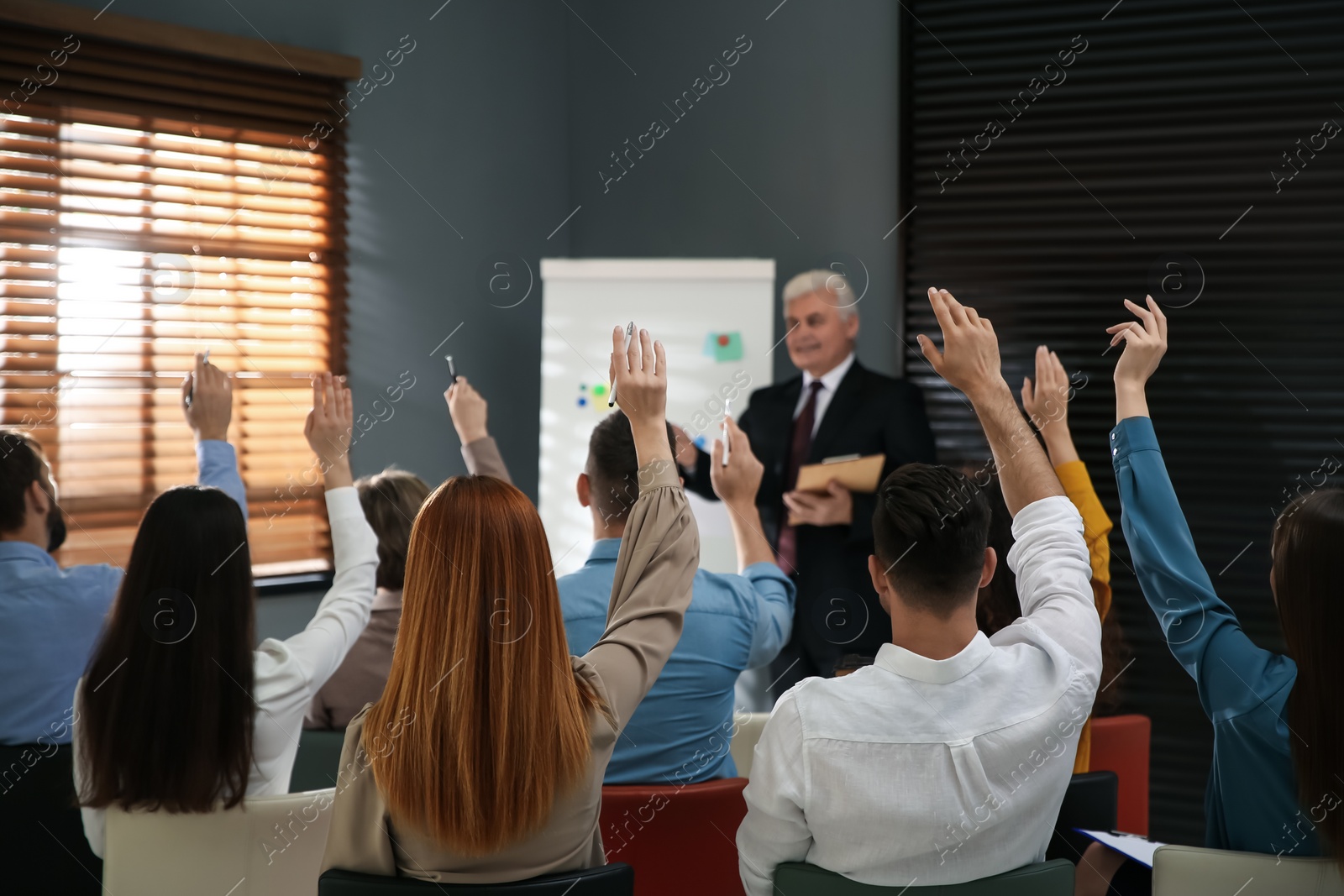 Photo of People raising hands to ask questions at seminar in office