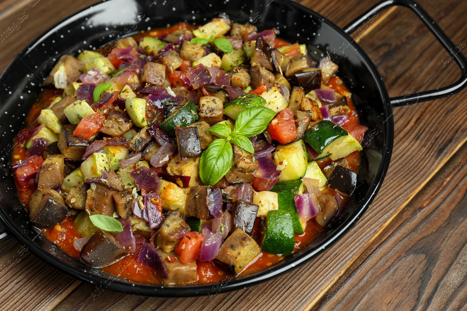 Photo of Delicious ratatouille in baking dish on wooden table, closeup