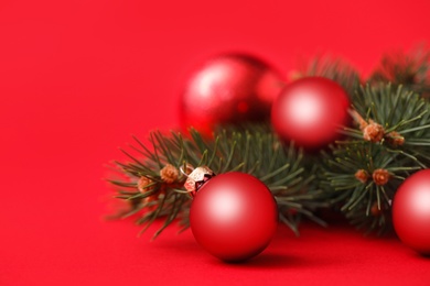 Photo of Beautiful Christmas balls and fir branches on red background