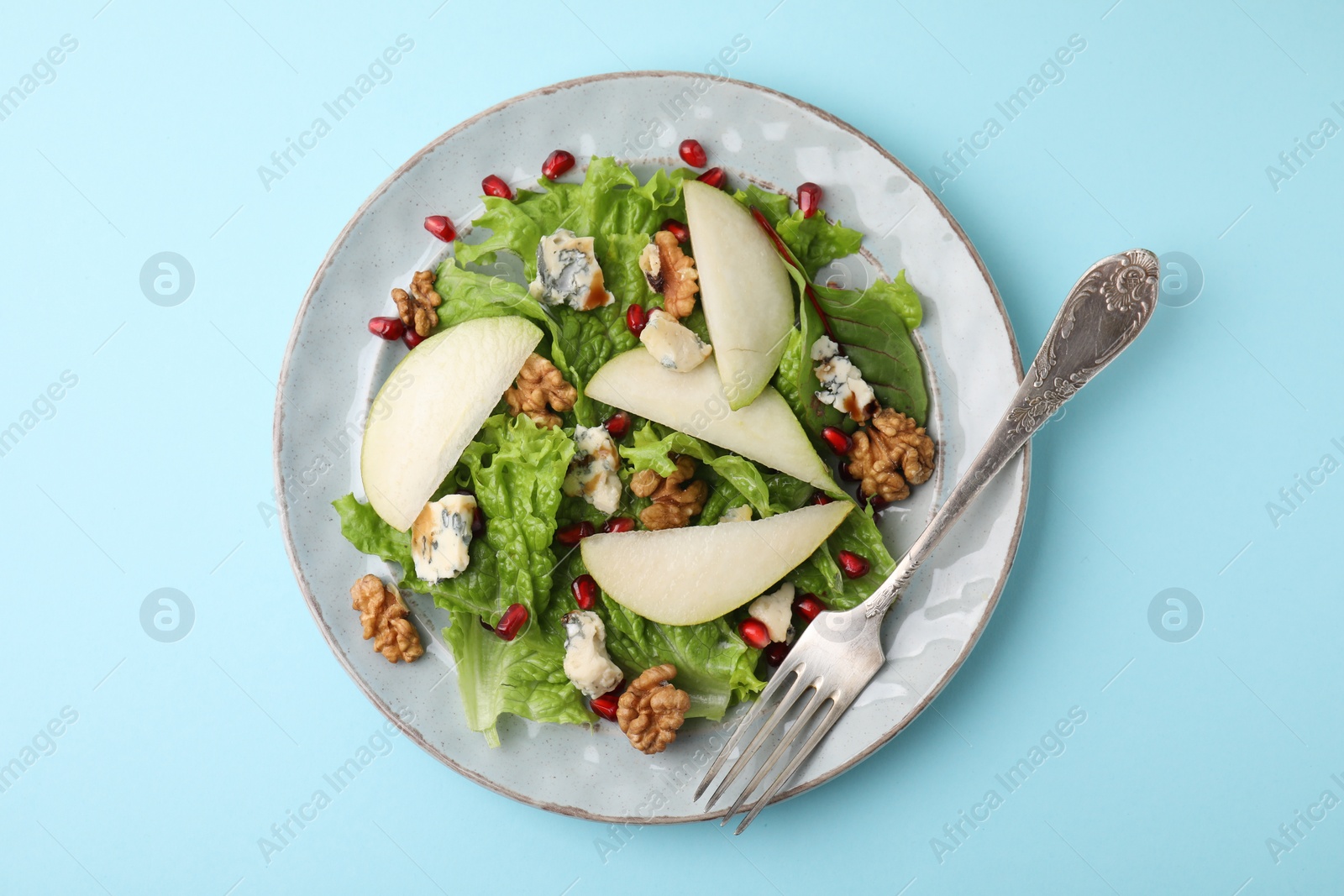 Photo of Delicious pear salad on light blue background, top view