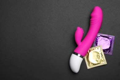 Vibrator and condoms on black background, top view with space for text. Sex game