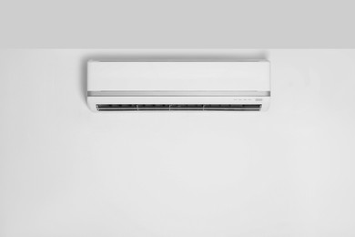 Modern air conditioner on white wall indoors. Space for text