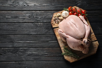 Board with raw turkey and ingredients on wooden background, top view. Space for text