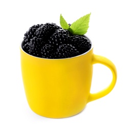 Yellow cup of tasty blackberries with leaves on white background