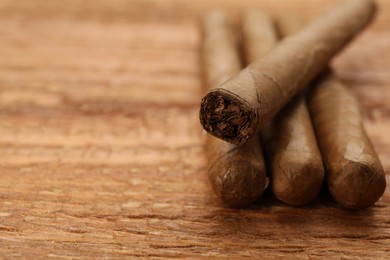 Photo of Many cigars on wooden table, closeup. Space for text