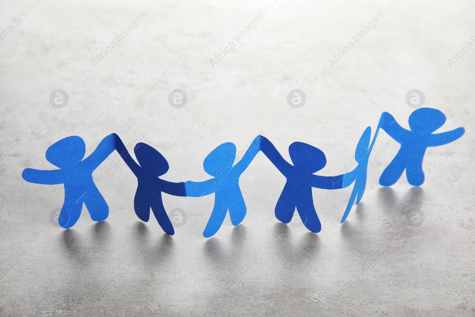 Photo of Paper people chain on light background. Helping and supporting concept
