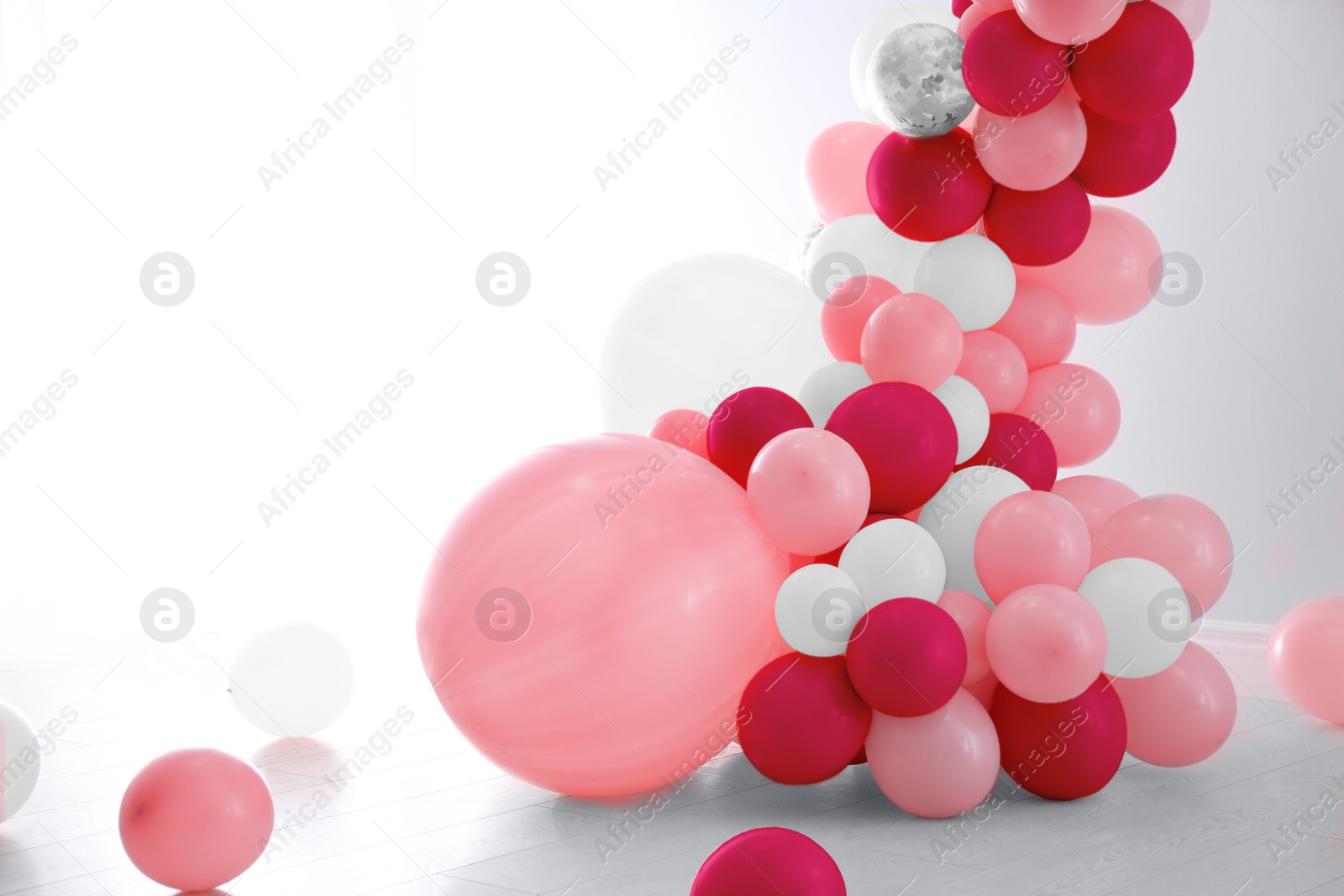 Image of Balloon garland near white wall in room. Festive decor