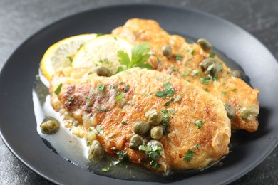 Photo of Delicious chicken piccata on black table, closeup