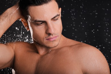 Man washing hair while taking shower on black background