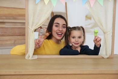 Mother and daughter performing puppet show at home