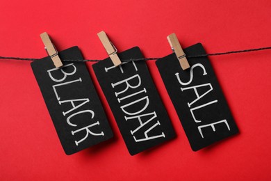 Tags with words Black Friday Sale on rope against red background