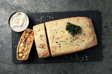 Photo of Delicious strudel with chicken and vegetables served on grey textured table, top view
