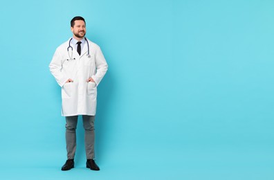 Photo of Smiling doctor with stethoscope on light blue background. Space for text