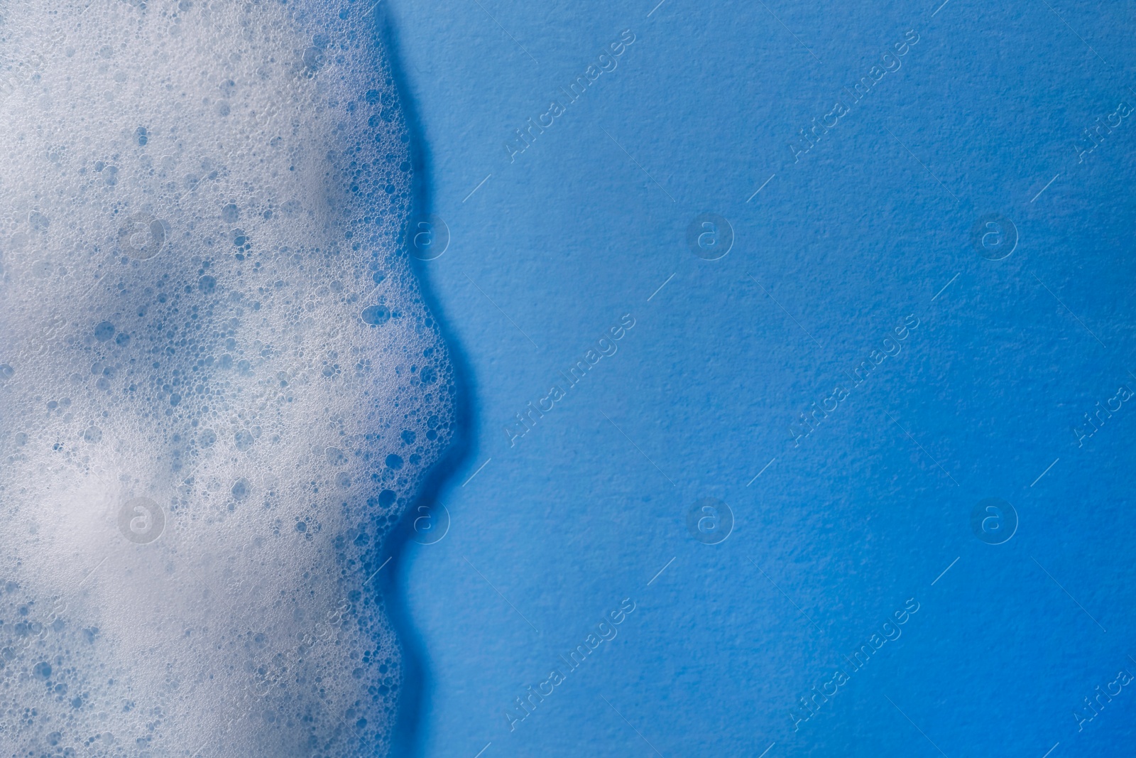 Photo of White foam on light blue background, top view. Space for text