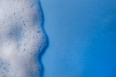 Photo of White foam on light blue background, top view. Space for text