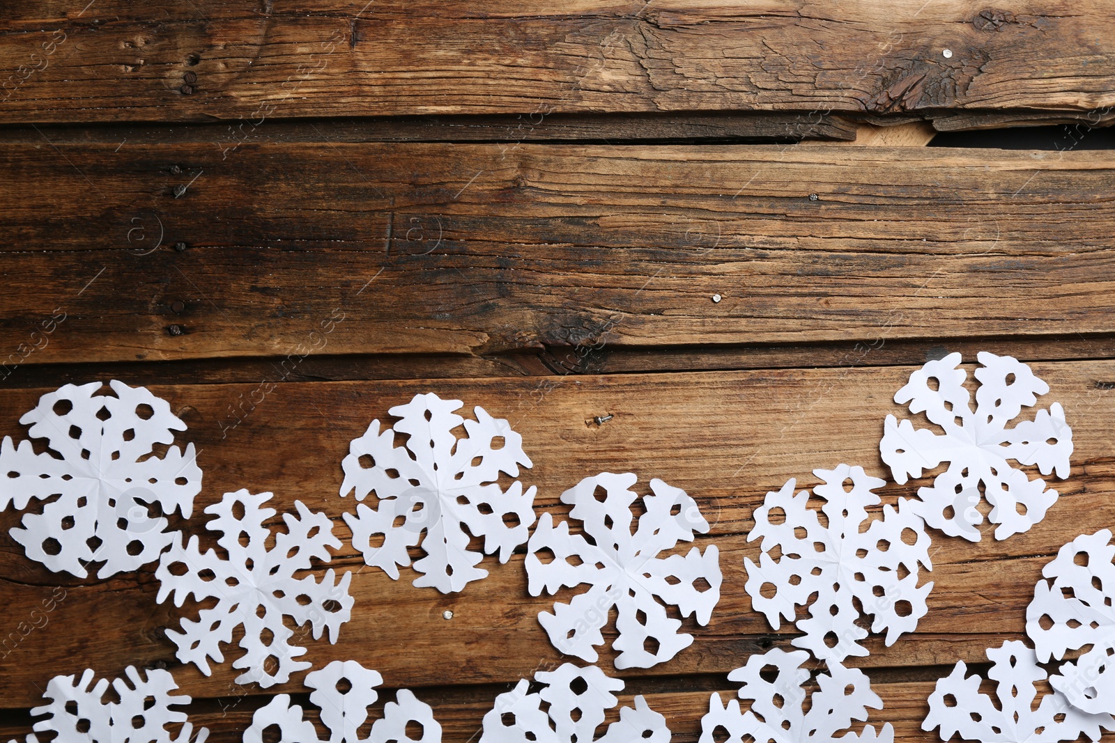 Photo of Many paper snowflakes on wooden background, flat lay. Space for text