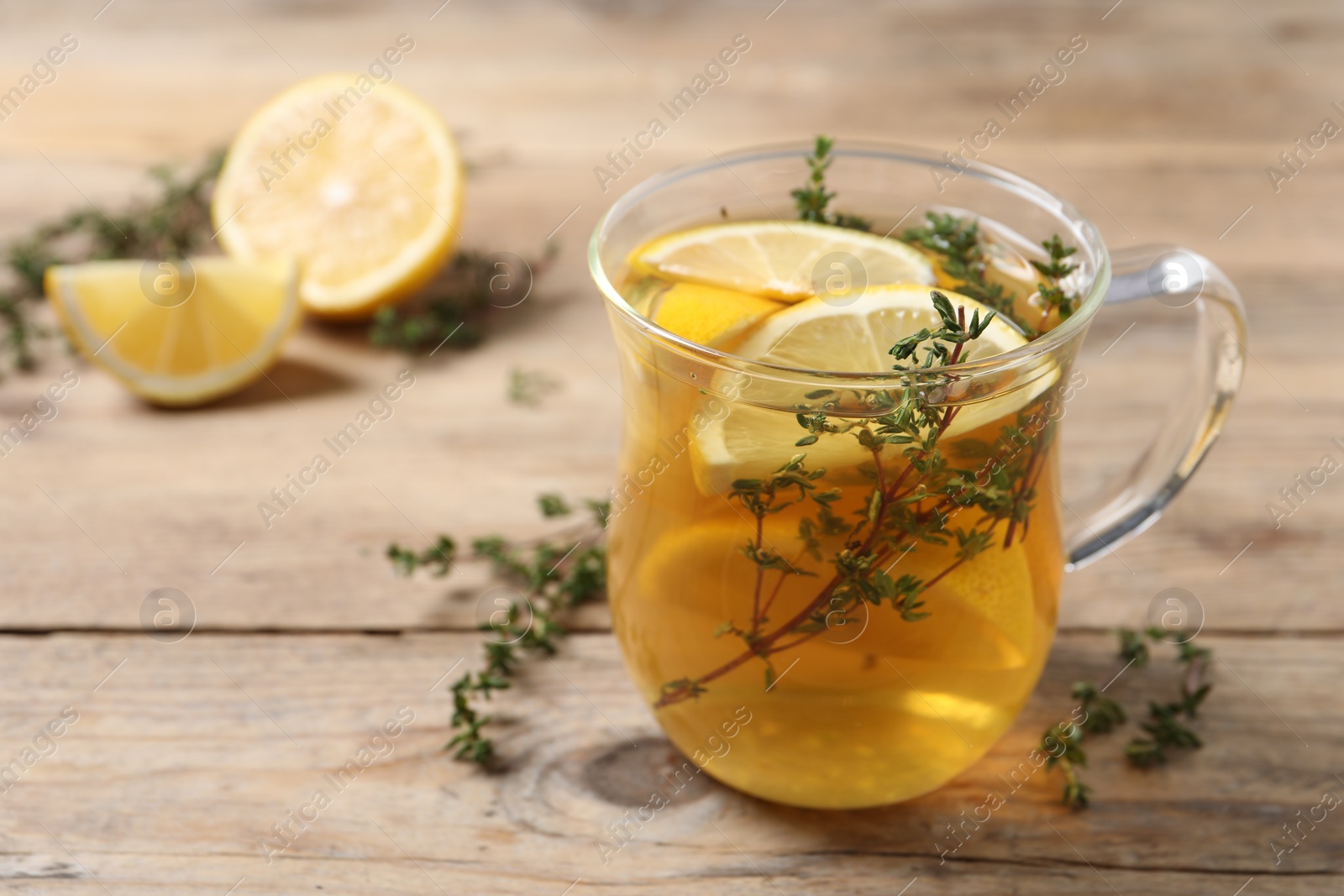 Photo of Aromatic herbal tea with thyme and lemon on wooden table, space for text