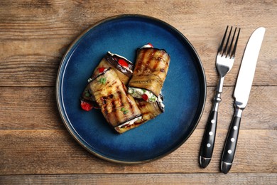 Delicious baked eggplant rolls served on wooden table, flat lay