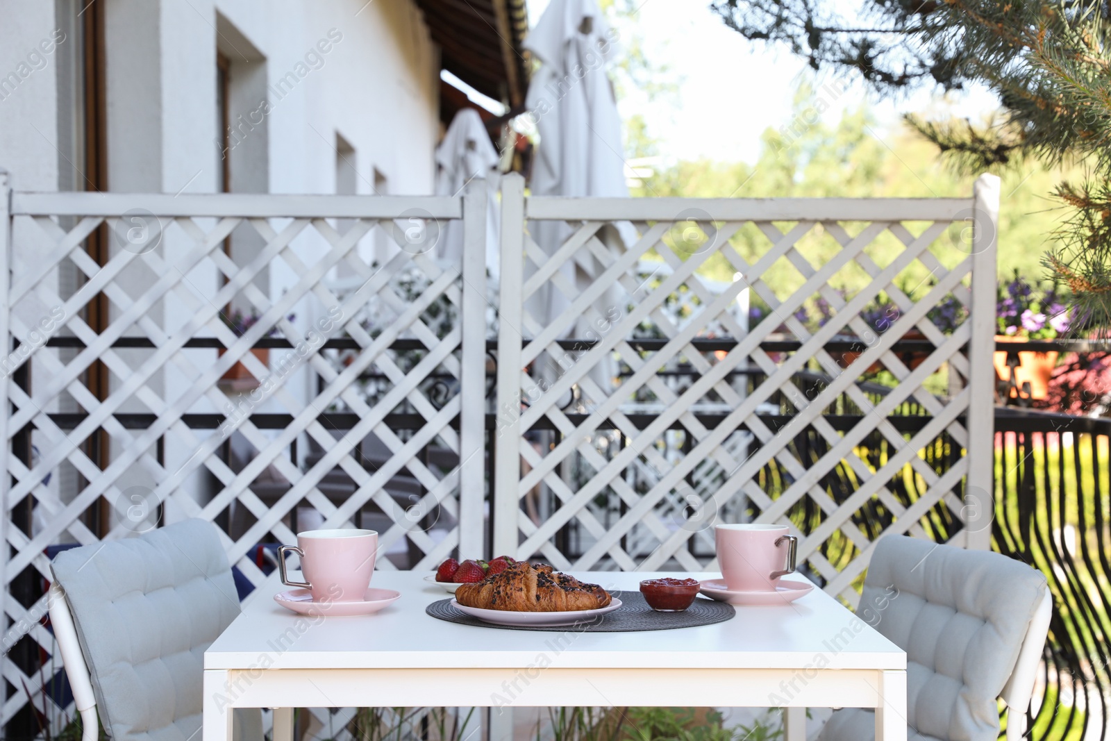 Photo of Outdoor breakfast with tea and croissants on white table on terrace