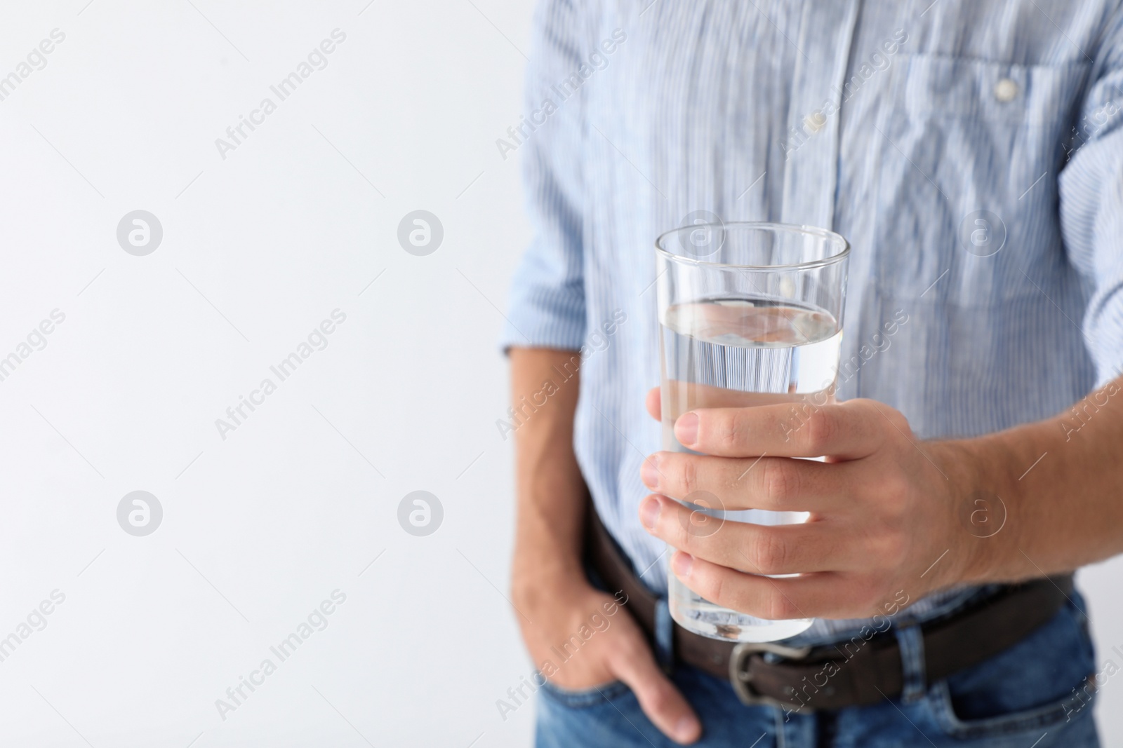 Photo of Man holding glass of pure water on white background, closeup. Space for text