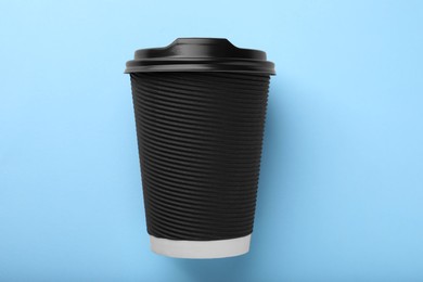 Photo of One paper cup on light blue background, top view. Coffee to go