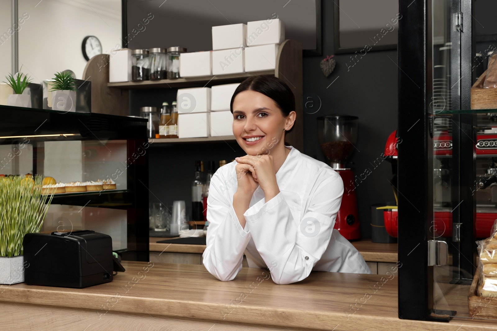 Photo of Portrait of happy baker at desk in her cafe