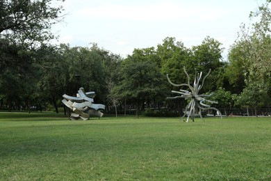 Picturesque view of beautiful park with metal figures on green grass