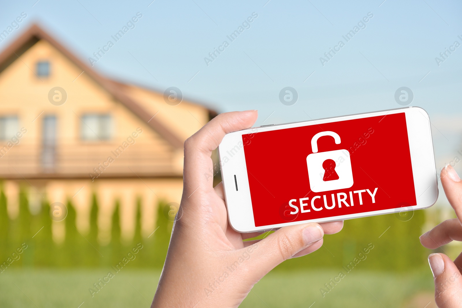 Image of Home security system. Woman with smartphone near her house outdoors, closeup