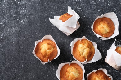 Delicious sweet muffins on black textured table, flat lay. Space for text