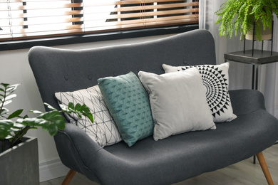 Photo of Stylish decorative pillows on grey couch indoors