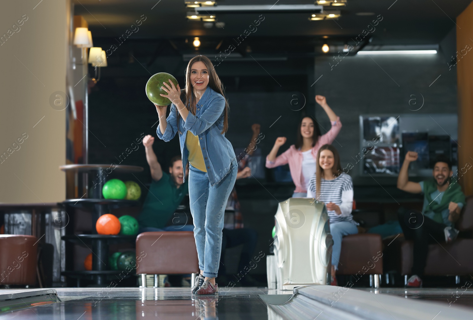 Photo of Young woman throwing ball and spending time with friends in bowling club