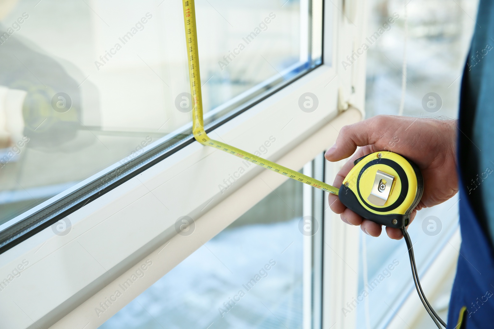 Photo of Service man measuring window for installation indoors, closeup